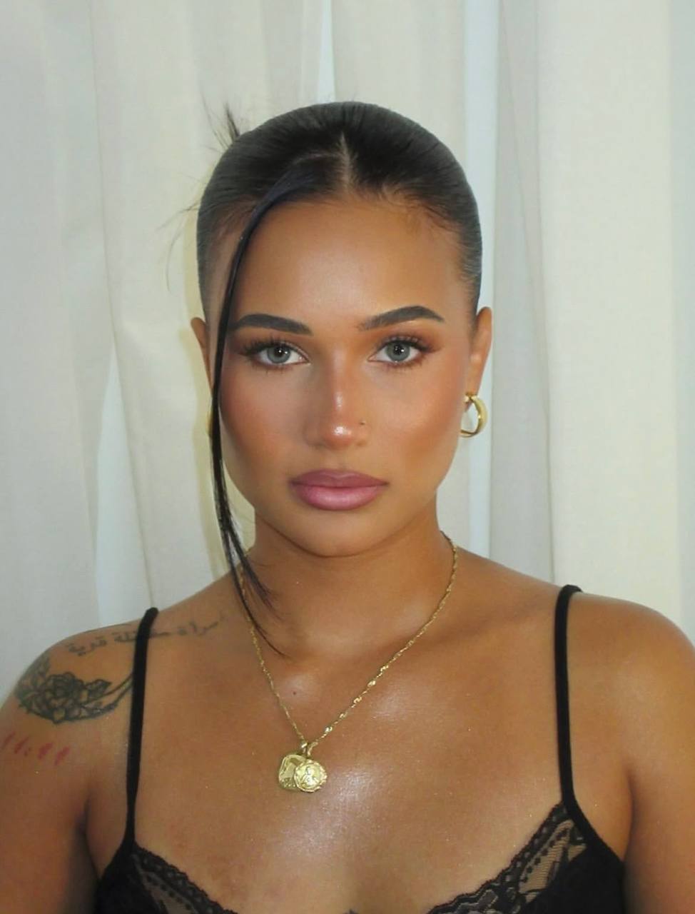 Close portrait with sleek dark hair, a defined eye, and a mauve lip